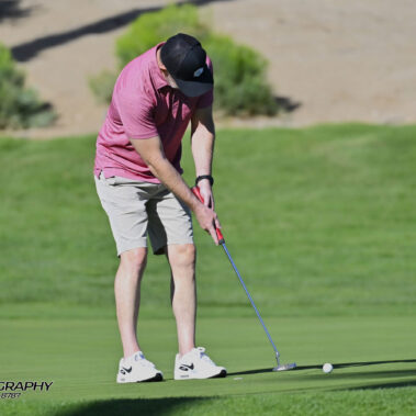 Male golfer swinging at golf ball.