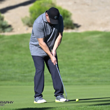 Male golfer swinging at golf ball.