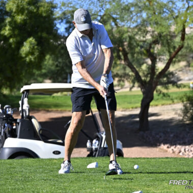 Male golfer swinging at golf ball.