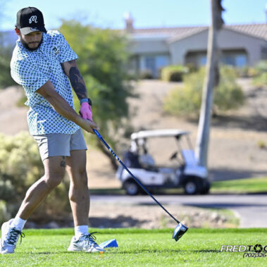 Male golfer swinging at golf ball.