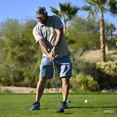 Male golfer swinging at golf ball.