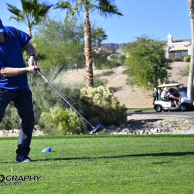 Male golfer swinging at golf ball.