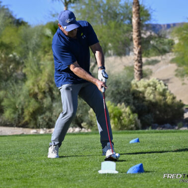 Male golfer swinging at golf ball.
