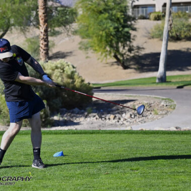Male golfer swinging at golf ball.