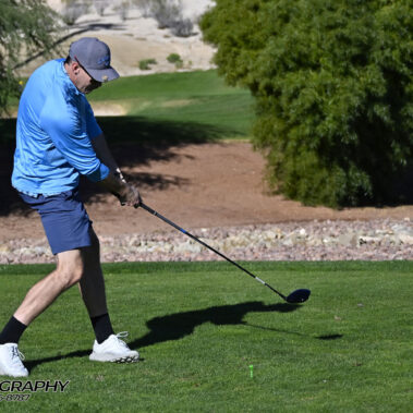 Male golfer swinging at golf ball.