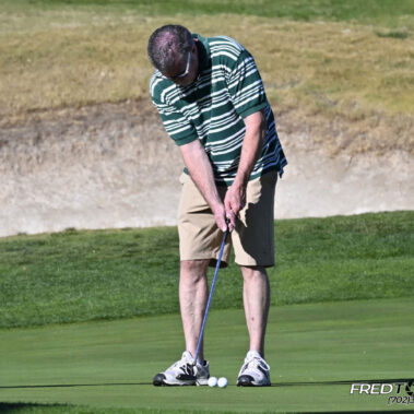 Male golfer swinging at golf ball.