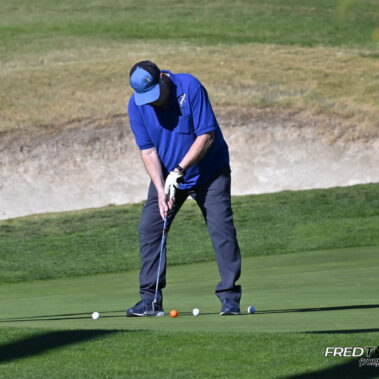 Male golfer swinging at golf ball.