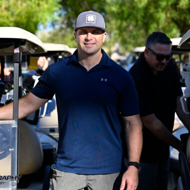 Male golfer standing at his golf cart.
