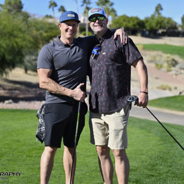 Two male golfer posing for a picture on golf course.